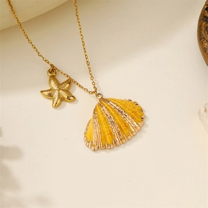 Detail of a gold starfish and yellow seashell pendant on a delicate chain necklace