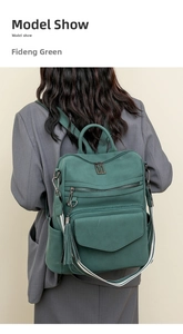 Deep green vintage backpack with fringe detail and striped straps shown on a model