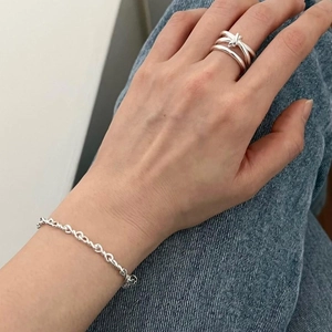 Detail of S925 silver knot ring and textured chain bracelet worn on hand in casual setting