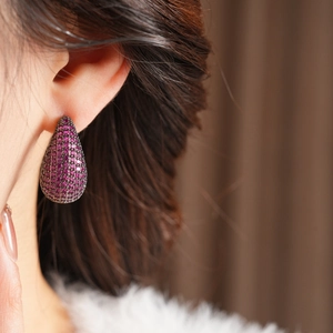 Close-up of vintage water-drop earrings with purple zircon inlays worn by model