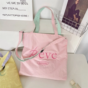 Detail of pink canvas tote bag with green handles and embroidered Reve lettering