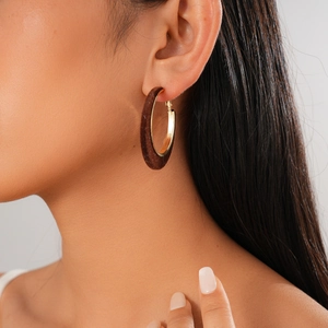 Close-up of a dark brown flocked geometric hoop earring with gold metal inner detail