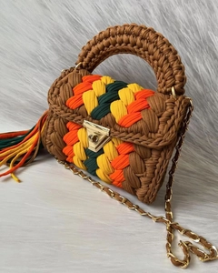 Close-up of handmade crochet bag with colorful tassels and golden metal chain strap