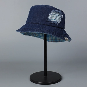 Detail of distressed blue denim bucket hat with plaid lining and small brand tag