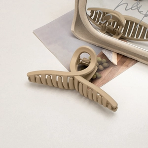Close-up of matte cream hair claw clip with cross teeth and durable metal spring