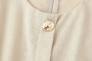 Dettaglio in lino beige con fibbia dorata e cerniera a scomparsa sul retro del vestito