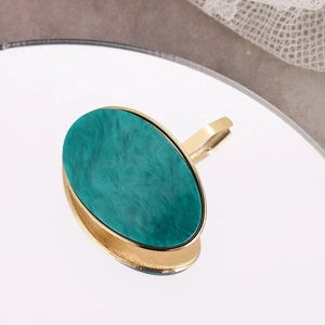 Detail of green oval acetate stone inlay on a golden alloy hair hook with lace background