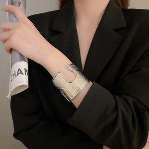 Detail of silver textured wide cuff bracelet worn by a model in black suit