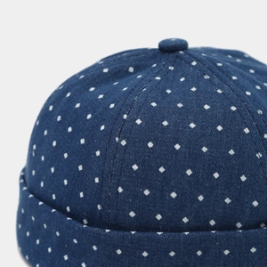 Close-up of dark blue denim docker hat with white square polka dot pattern and stitching