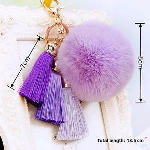 Detail of purple faux fur pompom keychain with silk tassels and golden hardware