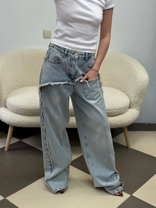 Detail view of light blue wide-leg jeans featuring distressed fringe and patchwork denim