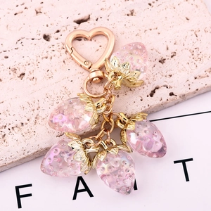Macro shot of 5 pink translucent strawberry pendants on a gold heart-shaped keychain clasp