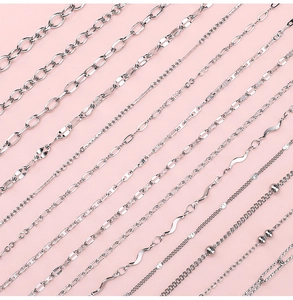 Macro shot of assorted silver stainless steel jewelry chains on a soft pink background