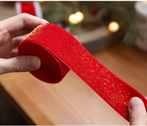 Close-up of red velvet Christmas ribbon with gold glitter and white stitched edges