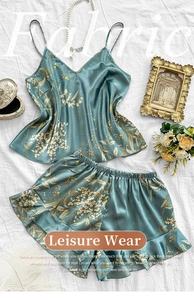 Flat lay of cyan floral silk pajama set with pearl necklace and vintage decor accessories
