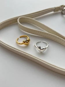 Detailed view of silver and gold irregular lava heart rings on a minimalist white surface