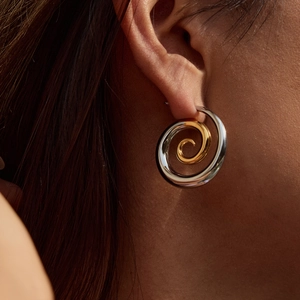 Close-up of two-tone spiral pearl earrings in gold and silver on a model's ear