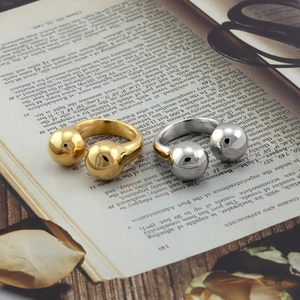 Detail verstellbarer Doppelball-Knotenringe in Gold- und Silberfinish auf einem Buch