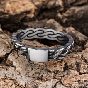 Close-up of vintage silver stainless steel ring with woven texture on natural bark background