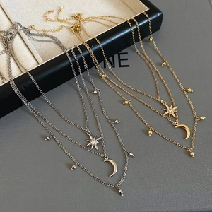 Detailed close-up of layered gold and silver star and moon pendant necklaces with rhinestones