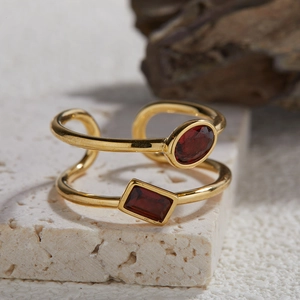 Close-up of double-layer gold ring with deep red garnet gemstones on stone base