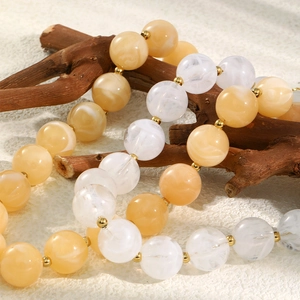 Dettaglio della collana di perle color ambra e marmo con distanziatori dorati