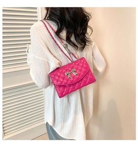 Hot pink quilted shoulder bag with silver bow detail shown worn on person shoulder
