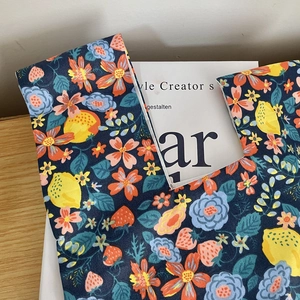 Close-up of dark blue floral canvas wristlet bag with lemon patterns on wooden surface