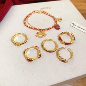 Detail of red gold-plated jewelry set with heart and rocking horse charms on white background