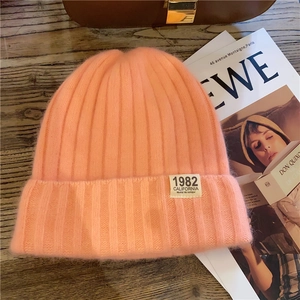 Detail of pink-orange ribbed knit beanie featuring an embroidered 1982 California label