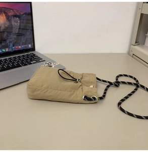 Detail of khaki drawstring crossbody phone bag with woven shoulder strap and nylon fabric
