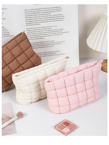 Detailed view of quilted nylon makeup bags in dark brown, cream, and soft pink colors