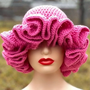Close-up of bright pink crochet hat featuring layered ruffle brim design on a model