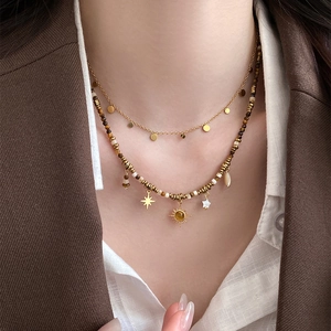 Detail of layered sun and star pendant necklace with brown tiger eye beads on a model
