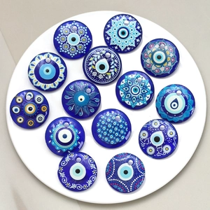 Detailed top view of thirteen assorted blue evil eye glass charms on a white plate
