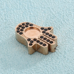 Macro shot of golden Hamsa pendant featuring black zircon inlay and central gemstone bezel