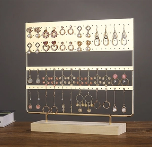 Detail of 3-tier gold metal jewelry stand with wooden base for earring and necklace storage