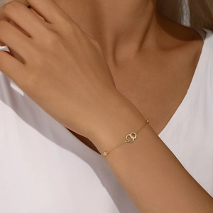 Close-up of a gold double-ring interlocking bracelet with zircon accents on a wrist