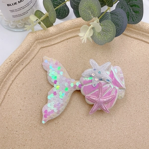 Detail of pink mermaid tail hair clip with iridescent sequins and glitter on tray