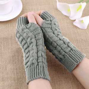 Close-up of sage green cable knit fingerless gloves with long wrist warmers on a desk