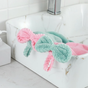 Pink and mint green coral fleece bow headbands for face washing on a marble vanity