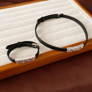 Detail of black leather chokers with silver engraved pendants on a velvet board