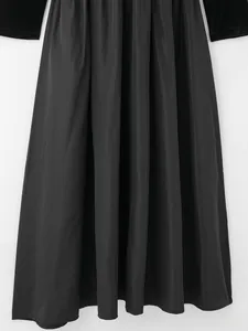 Gros plan détaillé de la texture plissée fine et du tissu noir brillant de l'ourlet de robe
