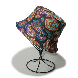 Detailed view of paisley pattern cotton bucket hat on a black wire display stand