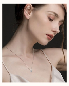 Detailed close-up of a six-prong moissanite pendant on a S925 sterling silver chain worn by a model