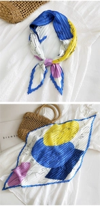 Dettaglio di un foulard in seta a pieghe con stampe geometriche colorate
