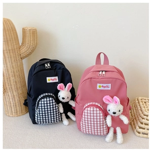 Detail of cute kids backpacks in black and pink with checkered pockets and plush bunny charm