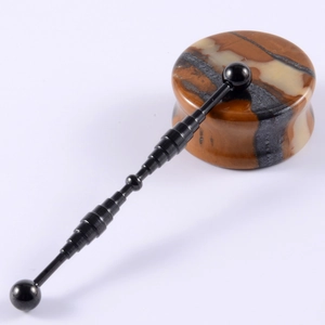 Detailed view of black metallic massage wand alongside a marbled agate gemstone tool