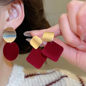 Détail de boucles d'oreilles géométriques en velours bordeaux et métal doré vintage
