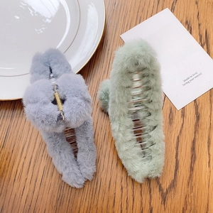 Large plush shark hair claw clips in grey and light green displayed on a wooden table